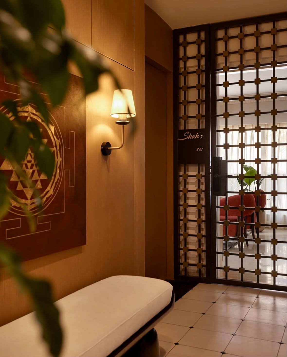 Hallway with a carved timber lattice screen, a wall lamp and a cushioned bench