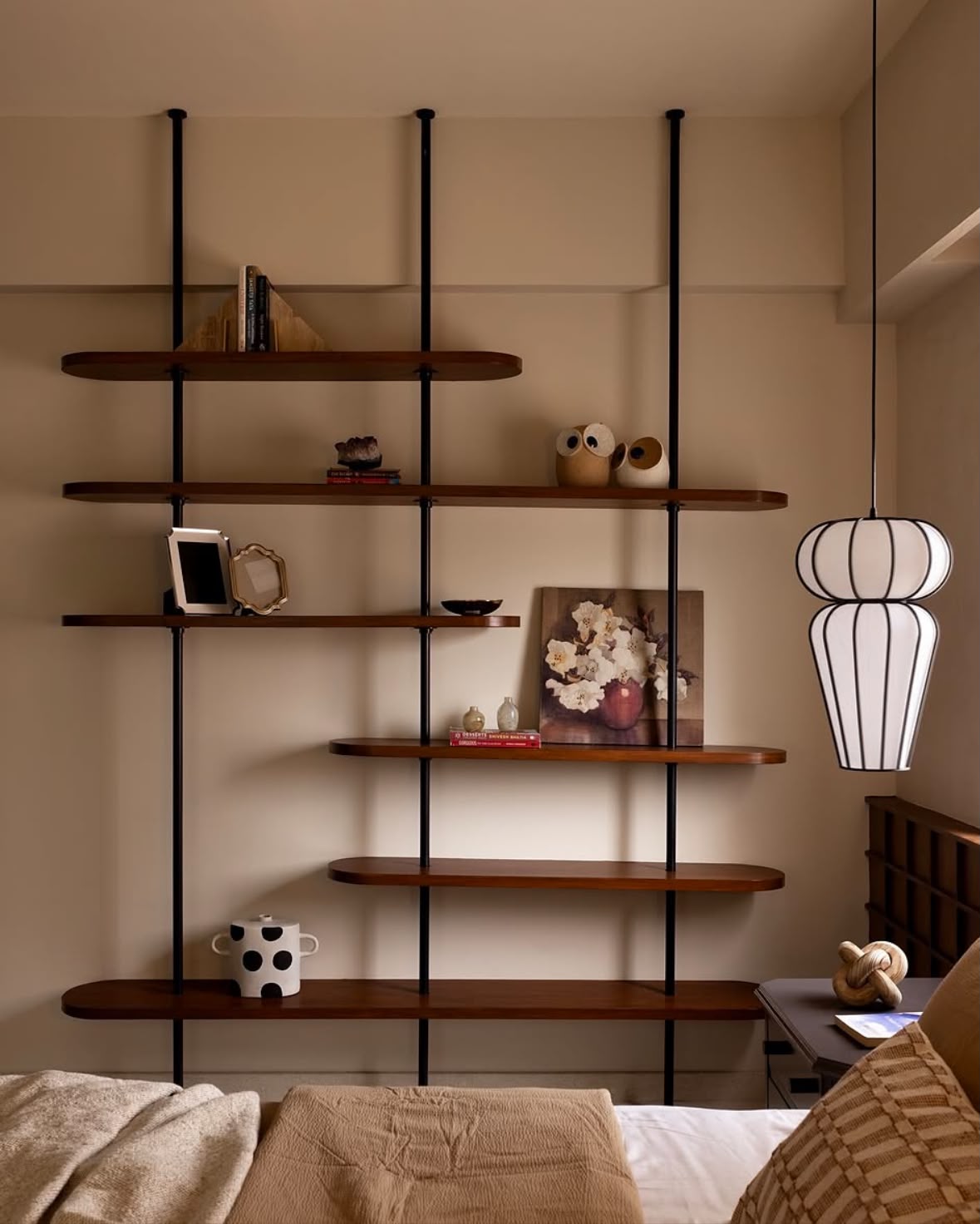 Bedroom wall with black-framed timber shelving and a paper pendant lamp