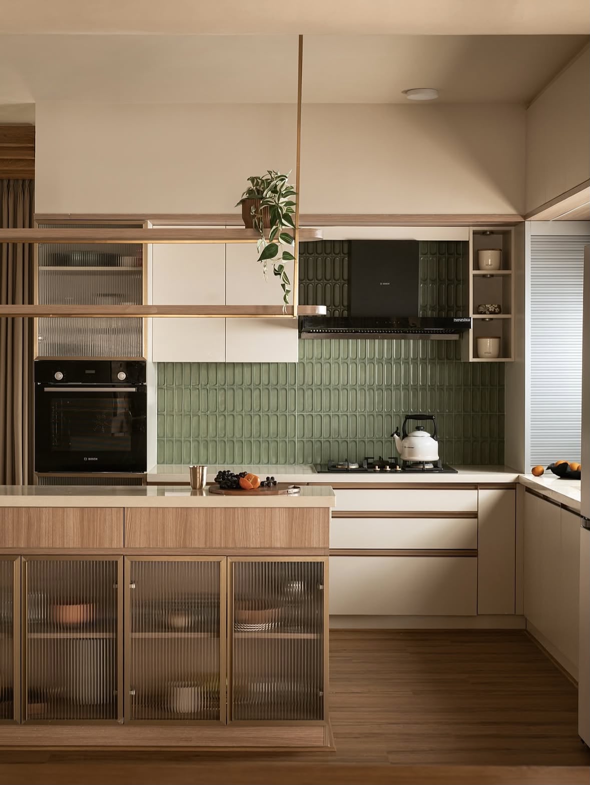 Kitchen with sage-green fluted tiles, a ribbed-glass island with brass edging and a built-in oven