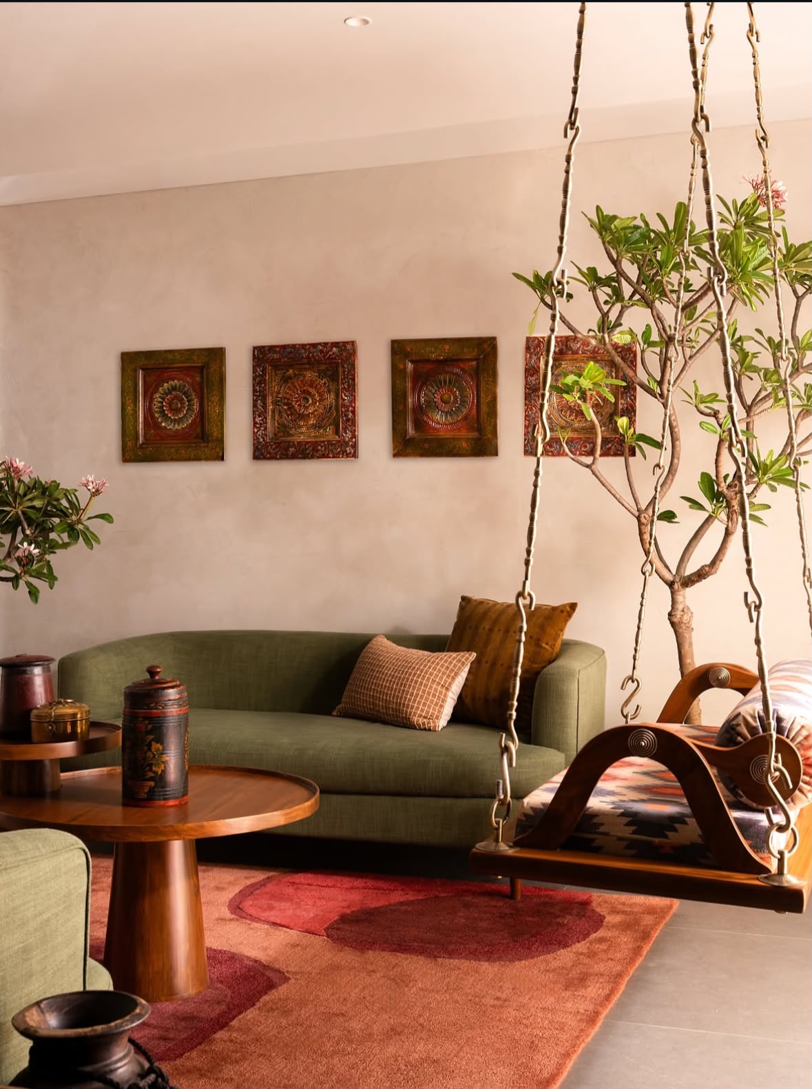 Living room with a green sofa, a wooden swing, framed brass wall art and a red rug